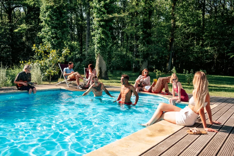 Ambiance conviviale et festive autour de la piscine d'une villa avec des amis partageant un verre