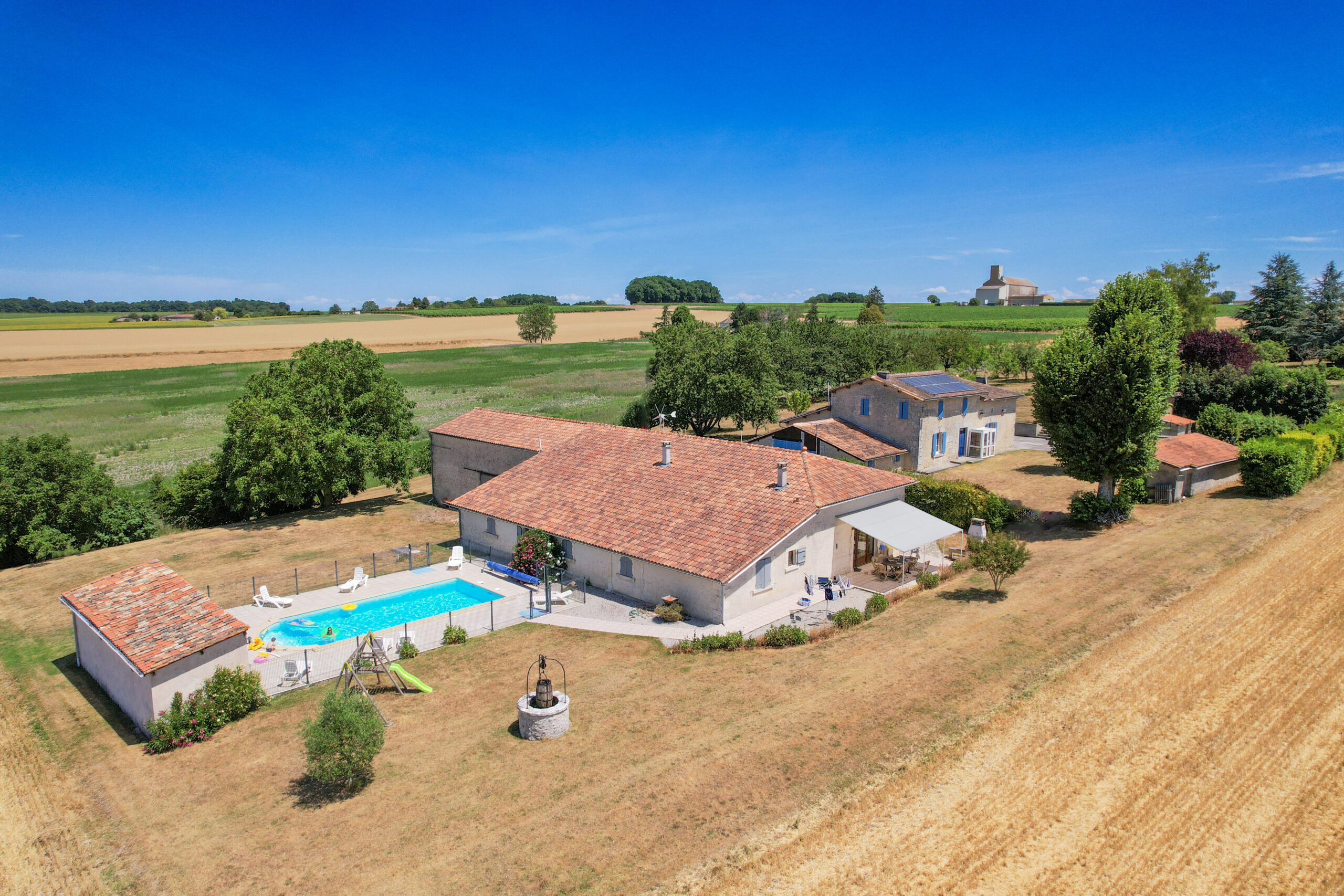 Vue aérienne de la villa Chez Penet à Berneuil (16) : maison en pierre, piscine extérieure clôturée, terrasse couverte et grand jardin, à 1h de Bordeaux